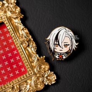 May include: A white and black anime character with red eyes and a red and orange flower pin. The character is wearing a white and black outfit. The character is on a gold picture frame with a red and white pattern.