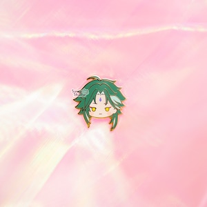 May include: A green and gold enamel pin featuring a cartoon character with green hair and a light blue gem on their forehead.