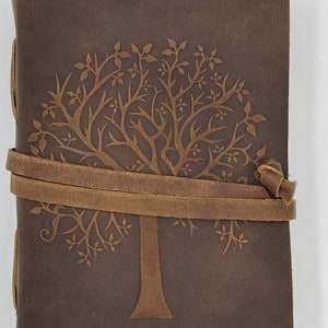 May include: A brown leather journal with a tree design embossed on the front cover. The journal has a brown leather strap closure.
