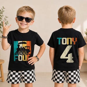 May include: A black short-sleeved t-shirt featuring a retro-style graphic of a steam train with the word FOUR in teal, yellow, and orange. The back of the shirt displays the name TONY and the number 4 in the same colorful, distressed font style.