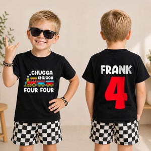 May include: A black t-shirt featuring a colorful train graphic with the text "CHUGGA CHUGGA FOUR FOUR" on the front and the name "FRANK" above a large red number "4" on the back, paired with black and white checkered shorts.