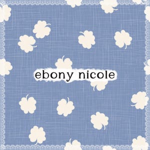 Op de afbeelding: Een lichtblauwe stof met witte klavervormige ontwerpen en een witte kanten rand. De tekst "ebony nicole" wordt weergegeven in een witte rechthoek in het midden van de afbeelding.