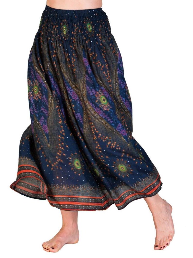 May include: A flowing, navy blue skirt with an elastic waistband and a vibrant, patterned design. The skirt features a repeating pattern of peacock-like motifs in shades of purple, green, and orange. The hemline is trimmed with a thin orange border.
