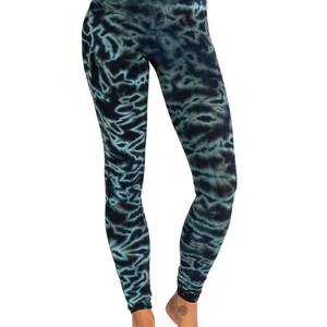 May include: Full-length leggings with a tie-dye pattern in shades of teal and navy blue. The leggings are form-fitting and made of a soft, stretchy material. The tie-dye design creates a unique, artistic look.