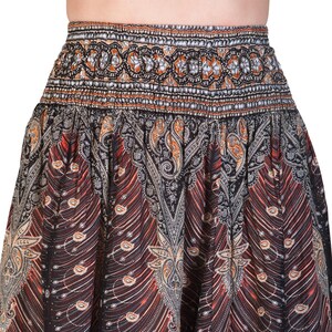 May include: A patterned skirt with a wide, elastic waistband. The skirt features a detailed design with paisley and feather-like patterns in shades of black, brown, orange, and white. The fabric appears to be lightweight and flowing.