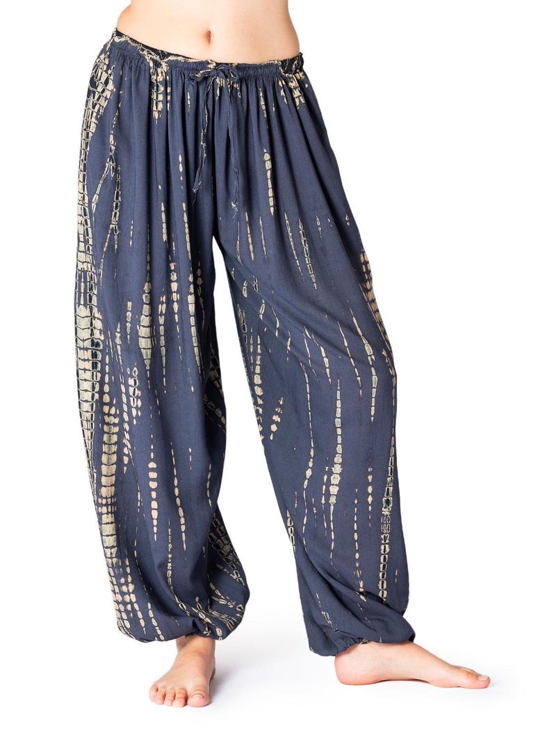 Dunkelgraue Loungehose mit beige vertikalem Tie-Dye-Muster, elastischer Bund und Knöchelbündchen, gerade geschnitten.