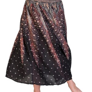 May include: A flowing, black skirt with a patterned design featuring red and tan feather-like shapes and white polka dots. The skirt has a wide waistband with an ornate, detailed pattern. The skirt is made of a lightweight fabric.