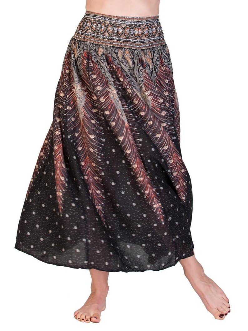 May include: A flowing, black skirt with a patterned design featuring red and tan feather-like shapes and white polka dots. The skirt has a wide waistband with an ornate, detailed pattern. The skirt is made of a lightweight fabric.