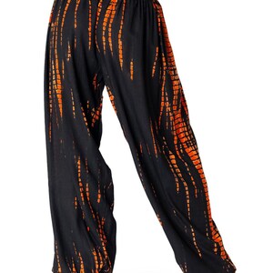 Locker geschnittene schwarze Chillhose mit vertikalem orangefarbenem Tie-Dye-Muster, elastischer Bund und Knöchelbündchen, Rückansicht.