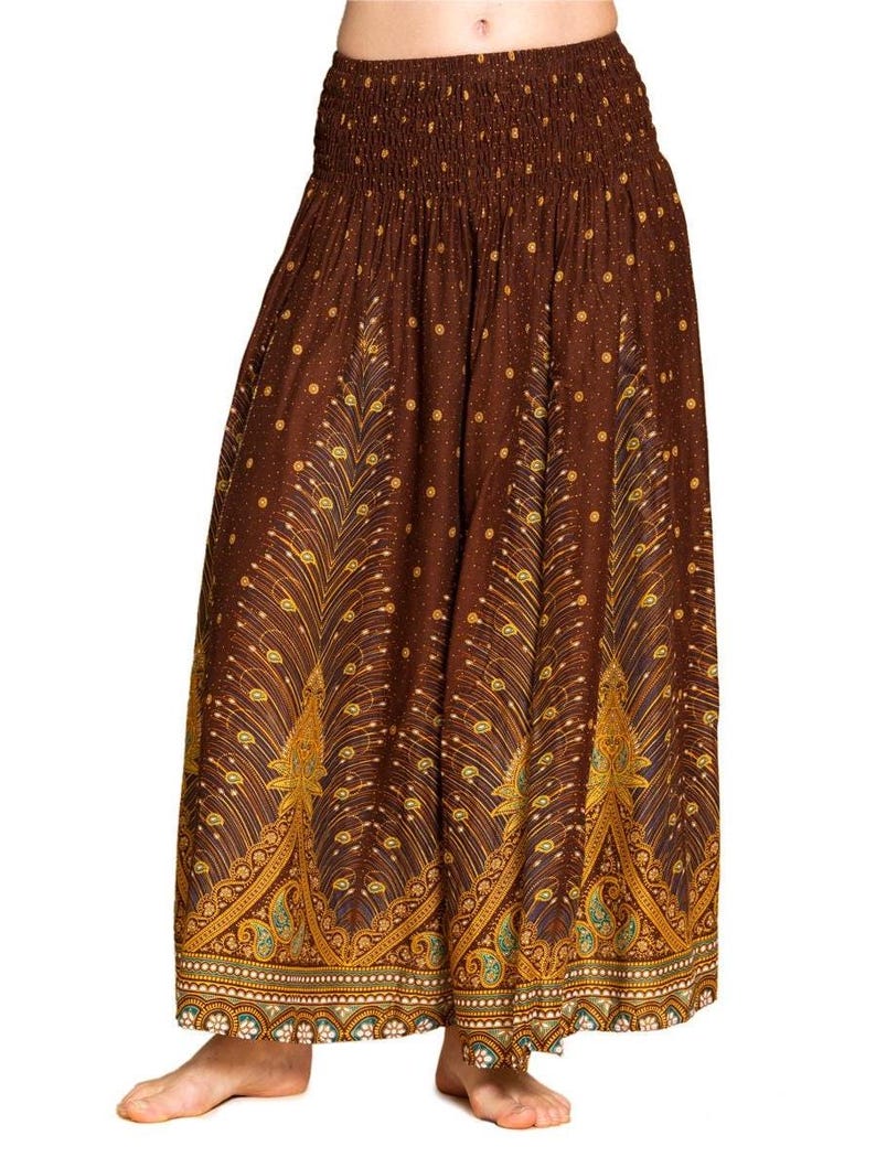 May include: Brown palazzo pants with an elastic waistband and a decorative peacock feather pattern. The pants feature a repeating pattern of gold and teal accents on a brown background. The bottom hem has a detailed border.