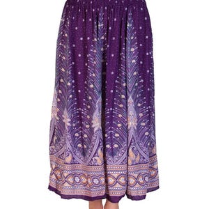May include: A long, flowing skirt in shades of purple with a decorative peacock feather pattern. The skirt features an elastic waistband and a detailed border with paisley and floral designs. The fabric has a soft, flowing appearance.
