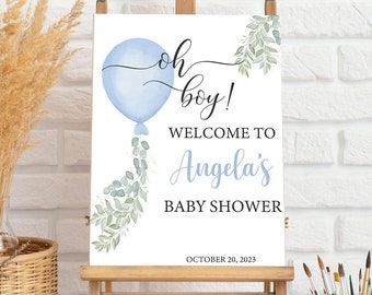 Puede incluir: Un letrero de baby shower sobre un caballete de madera. El letrero presenta una ilustración de globo azul con las palabras "oh boy!" y "Bienvenida a la fiesta de bienvenida de Angela" en una escritura elegante. También se muestra la fecha "20 de octubre de 2023".