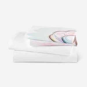 K&ouml;nnte beinhalten: Ein Stapel wei&szlig;er Bettw&auml;sche mit einem farbenfrohen abstrakten Design auf dem Oberlaken. Das Design zeigt ein regenbogenartiges Muster in Rosa-, Blau- und Gr&uuml;nt&ouml;nen.