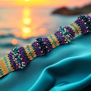 Puede incluir: Una pulsera de cuentas con un cierre dorado, que presenta un patrón de cuentas turquesas, doradas y moradas. La pulsera se muestra sobre una tela turquesa, con un atardecer borroso en el fondo, creando una estética vibrante y colorida.