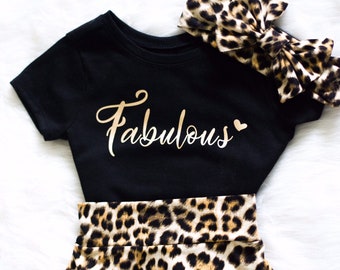 May include: Black and gold baby outfit with a leopard print skirt and headband. The shirt says "Fabulous" with a heart.
