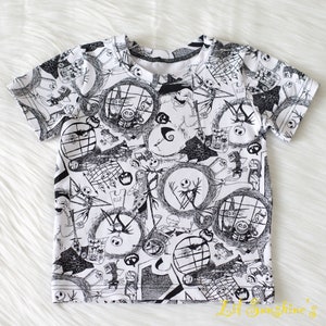 May include: A white t-shirt featuring a black and white print of characters from the film "The Nightmare Before Christmas".