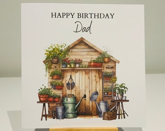 May include: A white card with a watercolor illustration of a shed with plants and gardening tools. The text "Happy Birthday Dad" is printed on the card.