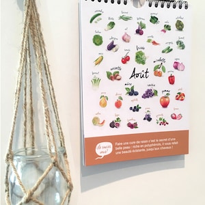 May include: A calendar featuring a colorful illustration of fruits and vegetables for the month of August. The text "Le saviez vous?" is in a speech bubble. The text below the speech bubble reads "Faire une cure de raisin c'est le secret d'une belle peau: riche en polyphenols, il vous refait une beaut&eacute; &eacute;clatante, jusqu'aux cheveux!"
