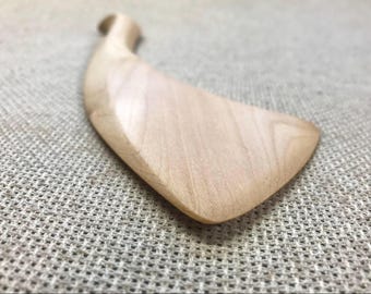 May include: A light-colored wooden kitchen spatula with a smooth, curved handle and a wide, flat blade. The natural wood grain is visible across the surface, showing a polished finish with a tapered edge that extends from the narrow handle.