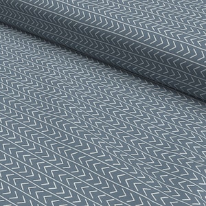 Può includere: Tessuto blu con un motivo a chevron bianco. Il tessuto è piegato a metà, mostrando il motivo su entrambi i lati.