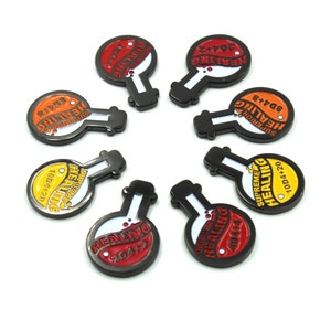 May include: Eight potion-shaped tokens with black borders and white, red, orange, and yellow centres. Each token features the word "HEALING" and other text, such as "2D4+2" and "10D4+20". The tokens are arranged on a white surface.