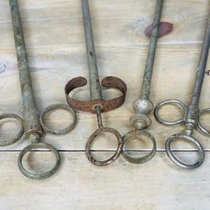 Peut inclure: Quatre outils anciens en m&eacute;tal avec de longs manches et des poign&eacute;es en forme d'anneau. Les outils ont une apparence vieillie et us&eacute;e avec des signes de rouille. Les manches sont cylindriques et les poign&eacute;es sont circulaires. Les outils sont dispos&eacute;s sur une surface en bois clair.