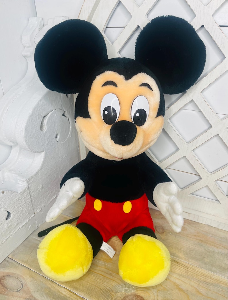 May include: A plush Mickey Mouse toy with black fur, large ears, yellow shoes, and a red and black outfit.