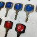 May include: Collection of vintage keys with numbered circular tags. The tags are predominantly blue and red, with numbers such as 2142, 2154, 2166, 2172, 143, and 375 clearly visible. The keys have a serrated edge and appear to be made of metal with a slightly aged or tarnished finish. The text 'THIS SIDE UP' is visible on some tags. These antique keys are ideal for vintage enthusiasts, collectors, or those seeking unique decorative items.