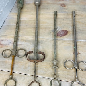 Peut inclure: Quatre outils anciens en m&eacute;tal, avec de longs manches et des extr&eacute;mit&eacute;s en anneau. Les outils pr&eacute;sentent une apparence vieillie, avec des signes de rouille et d'usure. Les manches sont cylindriques et les extr&eacute;mit&eacute;s en anneau varient en taille et en design.