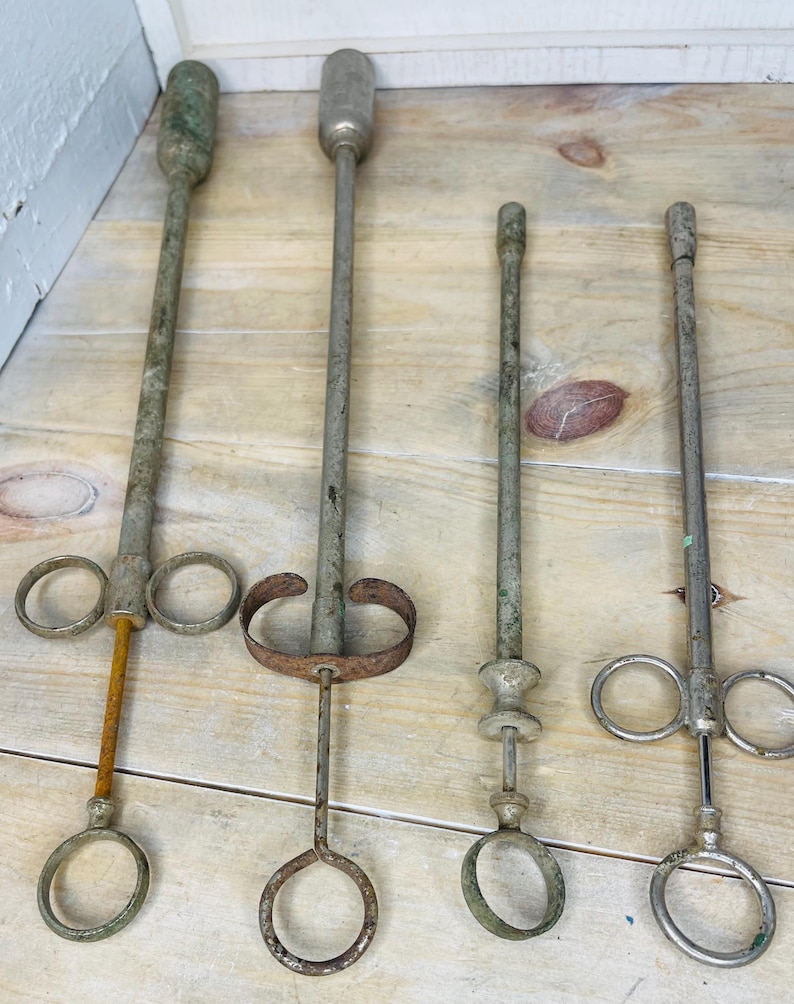 Peut inclure: Quatre outils anciens en m&eacute;tal, avec de longs manches et des extr&eacute;mit&eacute;s en anneau. Les outils pr&eacute;sentent une apparence vieillie, avec des signes de rouille et d'usure. Les manches sont cylindriques et les extr&eacute;mit&eacute;s en anneau varient en taille et en design.