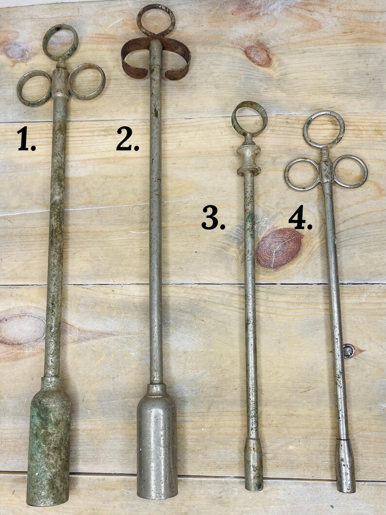 Peut inclure: Quatre outils anciens en m&eacute;tal de conceptions vari&eacute;es. Les outils ont de longues tiges minces et des sommets d&eacute;coratifs, notamment des anneaux et une poign&eacute;e incurv&eacute;e. Le m&eacute;tal a un aspect vieilli et patin&eacute;, certains pr&eacute;sentant des signes d'oxydation. Ils sont dispos&eacute;s sur une surface en bois.