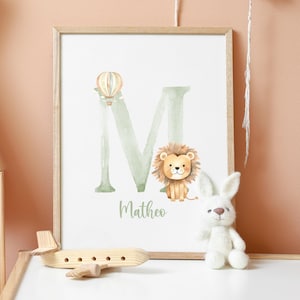 May include: A framed print with a watercolor illustration of the letter M in green, a hot air balloon, a lion, and the name Mattheo.