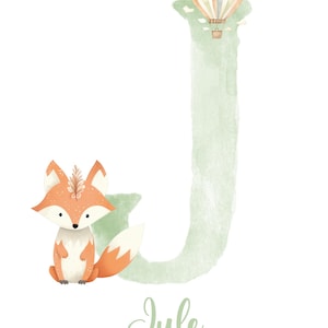 May include: A watercolor illustration of the letter J with a fox and a hot air balloon. The letter is green and the fox is orange and white. The hot air balloon is multi-colored and has a basket. The name "Jule" is written below the letter.