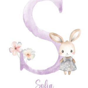 May include: A watercolor illustration of the letter S in purple with a cute bunny wearing a gray dress with white polka dots. The bunny is standing in front of the letter. There are two small pink and white flowers to the left of the letter. The name Sofia is written below the letter.