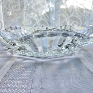 May include: A clear glass serving bowl with a wavy, scalloped edge. The bowl has a textured, ribbed design.