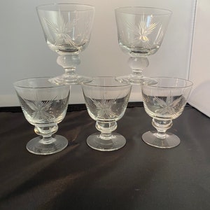 May include: Set of five clear glass stemmed drinking glasses with a starburst etched design.