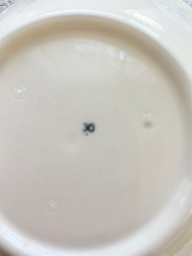 May include: The bottom of a white ceramic plate with a black number "30" printed on it.