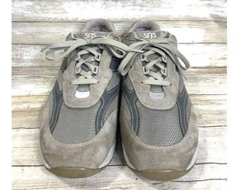 May include: A pair of gray suede and mesh sneakers with white laces. The sneakers have a black mesh panel on the side and the word "SAS" is printed on the tongue.