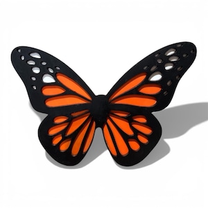 May include: A decorative butterfly with black and orange wings. The butterfly has a black body and the wings are black with orange accents. The wings have a detailed design with cut-out shapes.