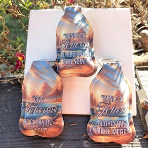 May include: Three colorful keychains with a sunset background and inspirational quotes in English, French, and Spanish. The quotes are "Give Jehovah the glory due his name", "Rendez à Jéhova, lui revient à son nom", and "Denle a Jehová la gloria que nombre merece".