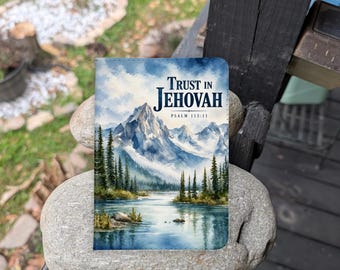Puede incluir: Una cubierta de libro rectangular con un paisaje en acuarela de montañas nevadas, un lago tranquilo y árboles de hoja perenne. El texto Trust in Jehovah y Psalm 115:11 está impreso en letras azul oscuro en la parte superior central.