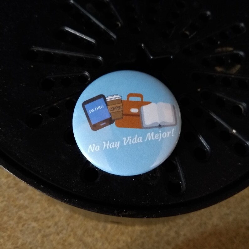 May include: A blue button with a white background and the text "No Hay Vida Mejor!" in white. The button features a cartoon illustration of a laptop, a cup of coffee, a briefcase, and an open book.