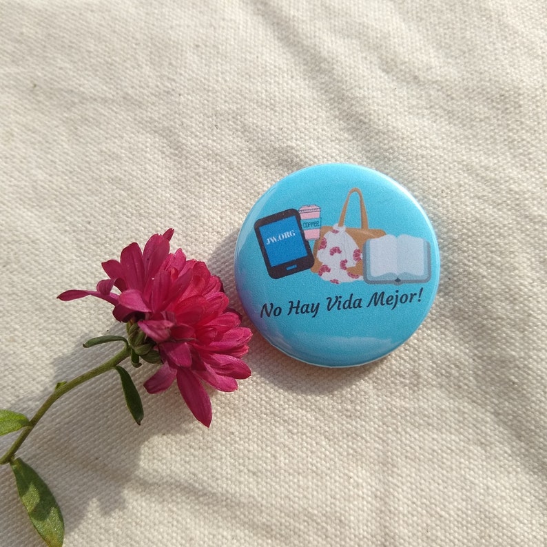 May include: A blue button with a white background and a graphic of a book, a handbag, a coffee cup, and a tablet with the text "jw.org". The text "No Hay Vida Mejor!" is printed below the graphic.
