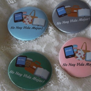 May include: Four round buttons with a light blue, gray, pink, and green background. Each button features a graphic of a book, a coffee cup, a phone, and a purse. The text "No Hay Vida Mejor!" is printed on each button.