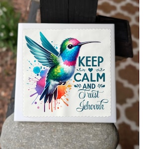 May include: A white ceramic tile with a colorful hummingbird and the text "Keep Calm and Trust Jehovah".