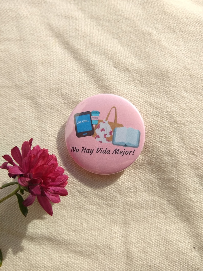 May include: Pink button with a cartoon illustration of a bag, a book, a coffee cup, and a phone with the text "jw.org". The text "No Hay Vida Mejor!" is printed below the illustration.