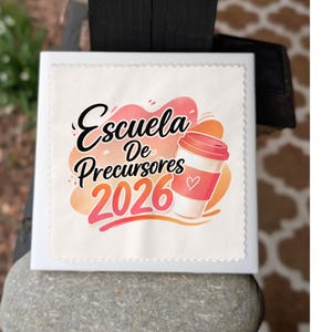 May include: A white square with a decorative edge featuring the text "Escuela De Precursores 2026" in black, pink, and orange. A coffee cup with a heart is also shown.
