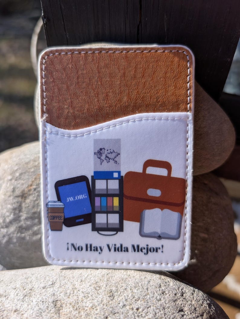 May include: A white leather card holder with a brown leather flap. The front of the card holder features a colorful illustration of a coffee cup, a phone, a briefcase, a book, and a magazine. The text "JW.ORG" and "&iexcl;No Hay Vida Mejor!" is printed on the card holder.