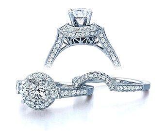 Puede incluir: Un anillo de compromiso de plata con una piedra central de diamante de corte cuadrado rodeada por un halo de diamantes más pequeños. La banda está adornada con detalles intrincados y diamantes más pequeños.