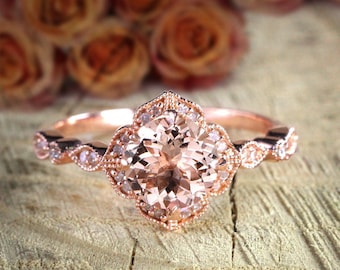 May include: A rose gold engagement ring with a large round morganite center stone surrounded by smaller diamonds. The ring has a delicate floral design and is set on a plain band.